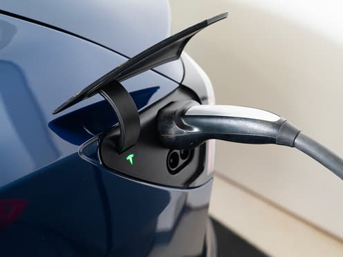 Zoom sur la prise de recharge d'une Tesla bleue.