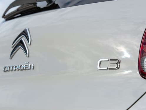 Zoom sur l'arrière d'une Citroën C3 blanche reprise par Aramisauto. On y voit le blason de la marque et du modèle.