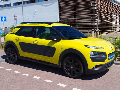 Une Citroën C4 Cactus jaune reprise par Aramisauto est garée en ville.