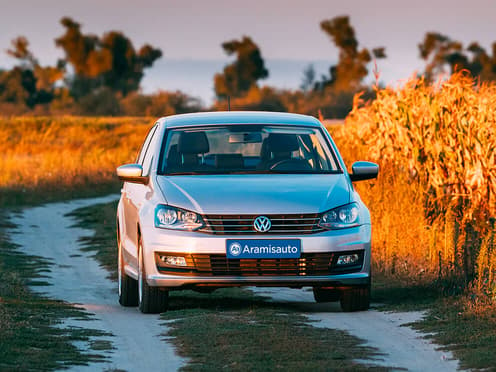 Une Volkswagen Polo reprise par Aramisauto est garée sur un chemin entre deux champs de maïs.