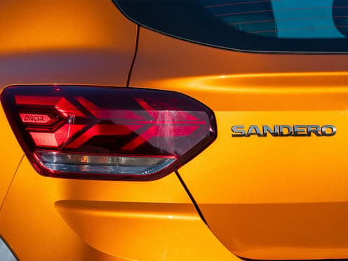 Zoom sur le phare arrière gauche d'une Dacia Sandero orange reprise par Aramisauto.