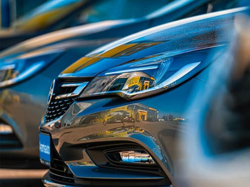 Plusieurs Opel reprise par Aramisauto et garée en ligne sur un parking.